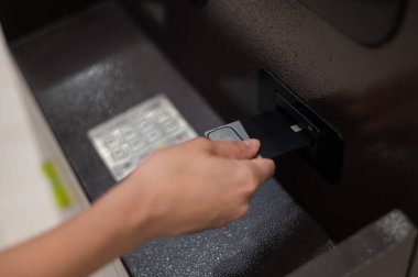 Meçhul kadın ATM 'ye banka kartı yerleştiriyor.