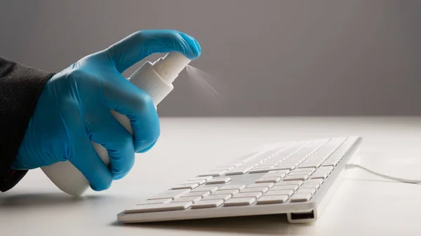 Close-up of a woman disinfects a white computer keyboard. Slow motion