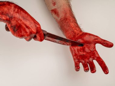 Eli kanlı bir adam kendini bıçakla kesiyor.