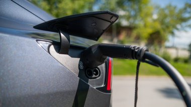 Yazın dışarıda siyah elektrikli araba şarj oluyor.