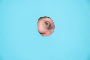 Mavi kağıt arka planda delikten dışarı bakan bir kadın.