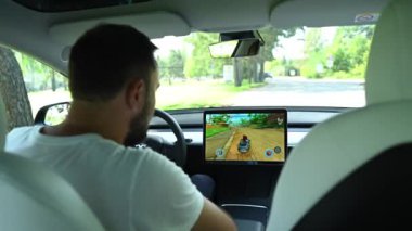 Novosibirsk, Rusya - 10.08.2022: Tesla araba sürerken oyun oynayan beyaz adam