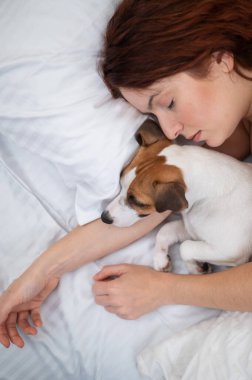 Kafkasyalı kadın yatağında uyuyor sevgili köpeğine sarılıyor.