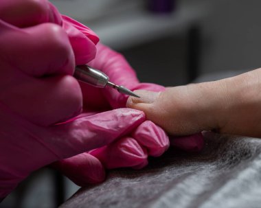 Usta müşteriye donanım pedikürü yapıyor. Kütikül tedavisi