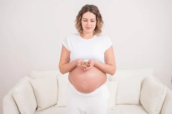 妊娠中の女性は一握りのクルミを持っている — ストック写真