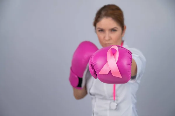穿着粉色拳击手套 灰色背景带粉色带子的女医生 与乳腺癌作斗争 — 图库照片
