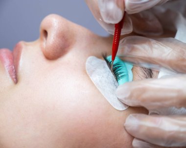 Usta kirpikleri kaplamak için çok fonksiyonlu bir araç kullanır