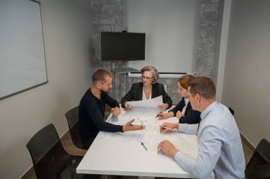 Dört meslektaşı bir ofisteki konferans odasının planlarını tartışıyor. Mühendis ve mimarların beyin fırtınası