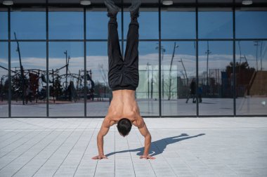 Bir adam panoramik pencerelere karşı amuda kalkıyor.