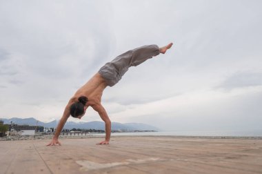 Çakıl taşlı plajda ters takla atan beyaz bir adam.