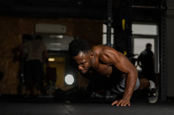 African american man doing one arm push ups in the gym