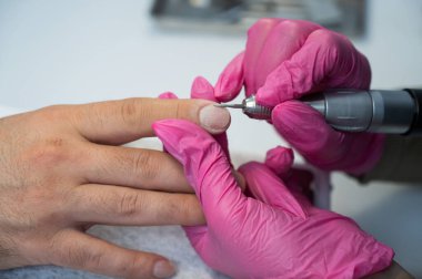 Usta, erkek müşteriye donanım manikürü yapıyor.