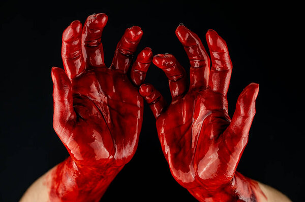 Womens hands in blood on a black background