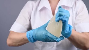 Bir plastik cerrah silikon göğüs implantlarının gücünü onları sıkarak gösterir.