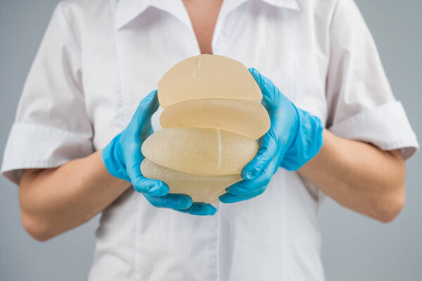 The plastic surgeon holds breast silicone implants