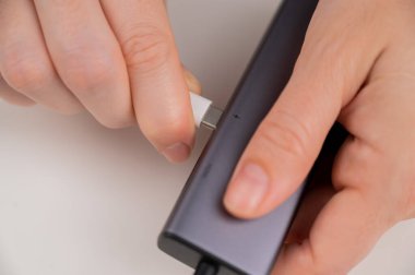 Bir kadın siyah bir limana beyaz tip C kablosu yerleştiriyor.