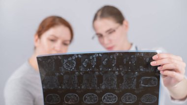 Kadın doktor, kadın hastaya iç organların MRI 'sını açıklıyor.