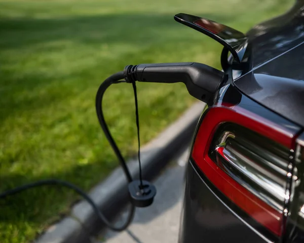 夏に屋外で充電ブラック電気自動車 — ストック写真