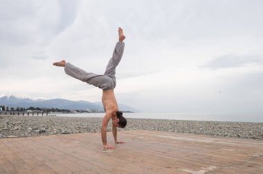 Çakıl taşlı plajda ters takla atan beyaz bir adam.