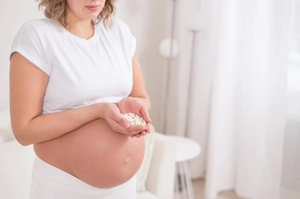 Těhotná Žena Drží Hrst Bílých Pilulek — Stock fotografie