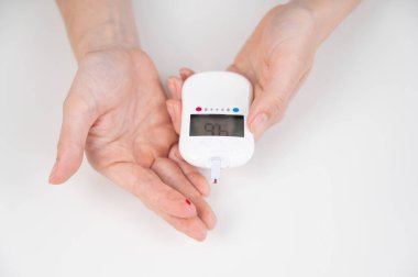 Kadın kan şekerini glukometreyle ölçüyor.