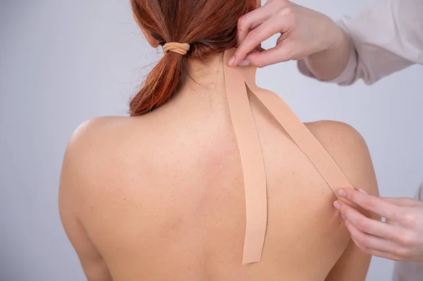 女性医師Glues Kinesioテープオンザ患者肩 — ストック写真