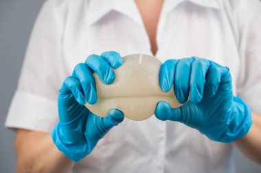Bir plastik cerrah silikon göğüs implantlarının gücünü onları sıkarak gösterir.