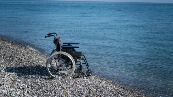 Una Sedia Rotelle Vuota Una Spiaggia Rocciosa — Foto Stock