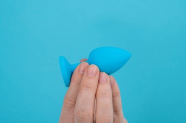 Mavi arka planda mavi anal tıpa tutan bir kadın.