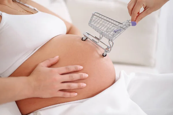顔のない妊娠中の女性とともにショッピングカート上の彼女の腹 — ストック写真
