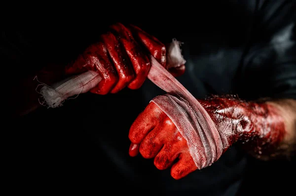 一个浑身是血的男人用绷带包住双手 — 图库照片