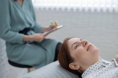 Orta yaşlı bir kadın kanepeye uzanıp bir psikologla konuşuyor.