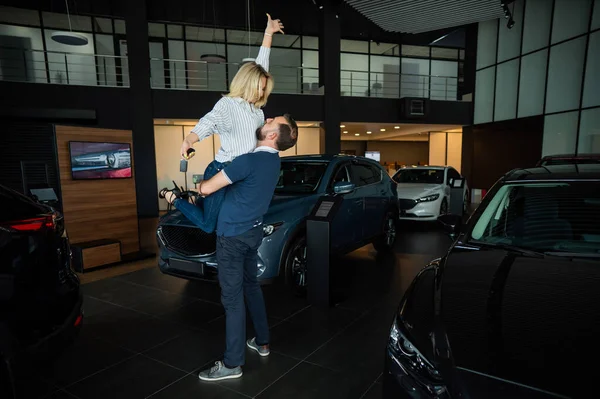 Feliz Casal Caucasiano Abraçando Enquanto Compra Carro Novo Uma Concessionária — Fotografia de Stock