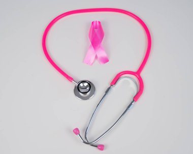 Beyaz arka planda pembe kurdele ve steteskop. Göğüs kanseriyle mücadele kavramı