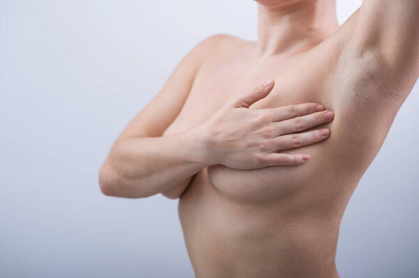 Caucasian woman self checks for breast cancer on white background. Copy space