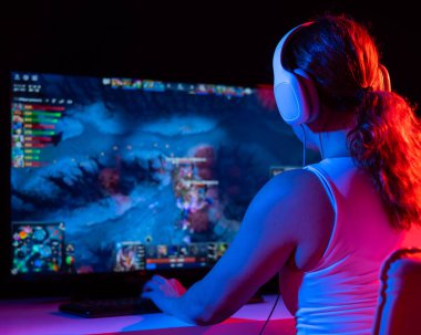 Kafkasyalı bir kadının karanlıkta neon ışıkta bilgisayar oyunu oynaması.