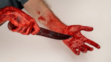 Eli kanlı bir adam kendini bıçakla kesiyor.