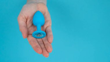 Mavi arka planda mavi anal tıpa tutan bir kadın.