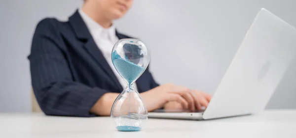 Business woman keeps track of time on an hourglass while working
