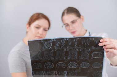 Kadın doktor, kadın hastaya iç organların MRI 'sını açıklıyor.