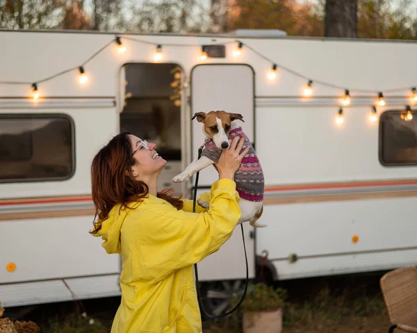 Kızıl saçlı beyaz kadın bir köpeğe sarılıyor ve bir karavanda yaşıyor. Karavanla seyahat et.