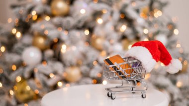 Noel hediyesi alışverişi konsepti. Kredi kartı Noel ağacının yanındaki alışveriş arabasında.