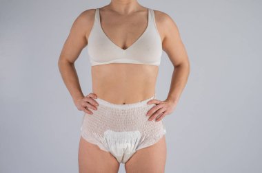 Beyaz arka planda yetişkin bezli bir kadın. İdrarını tutamama sorunu