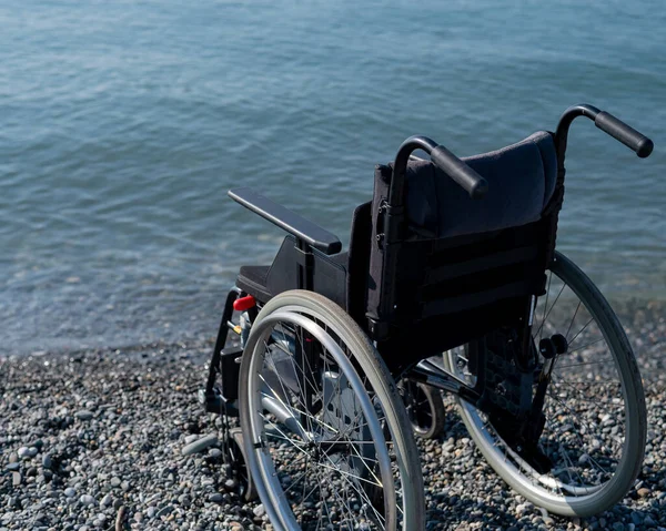 一个空轮椅在岩石海岸上 — 图库照片