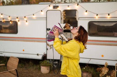 Kızıl saçlı beyaz kadın bir köpeğe sarılıyor ve bir karavanda yaşıyor. Karavanla seyahat et.