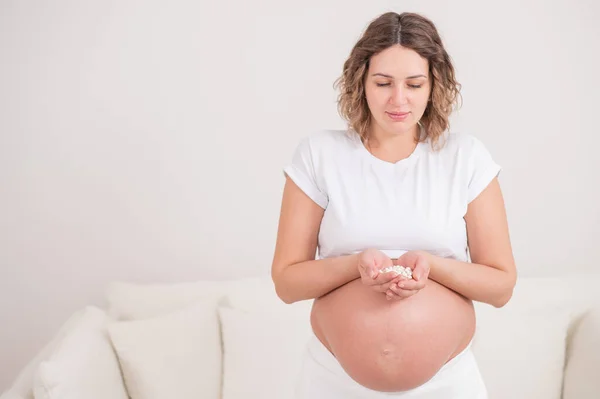 Een Zwangere Vrouw Houdt Een Handvol Witte Pillen Vast — Stockfoto