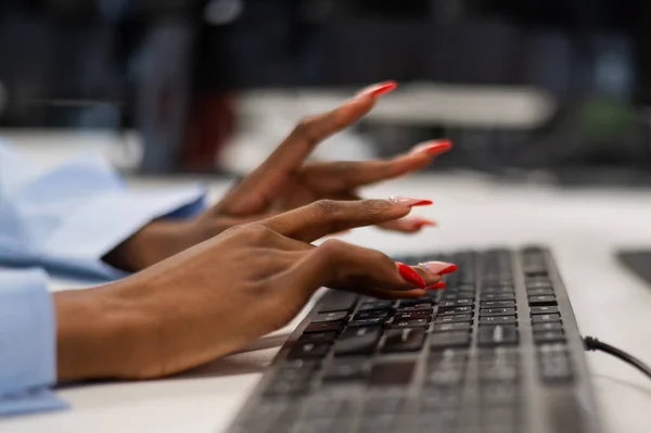 African woman is typing on the keyboard. Close-up of female hands of an office worker