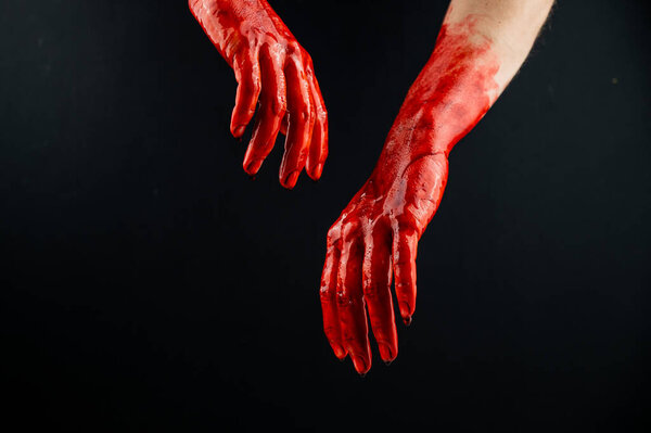 Womens hands in blood on a black background