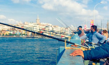 EMINONU, ISTANBUL / TURKEY - NOVEMBER 15, 2021: Fishermen catch fish from the Galata bridge next to Eminonu pier
