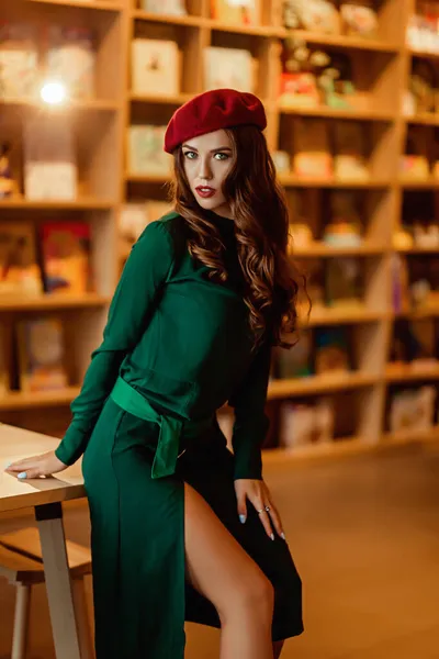 Young european woman in a bookstore, a brightly dressed lady in a beret with a book — Stock Photo, Image